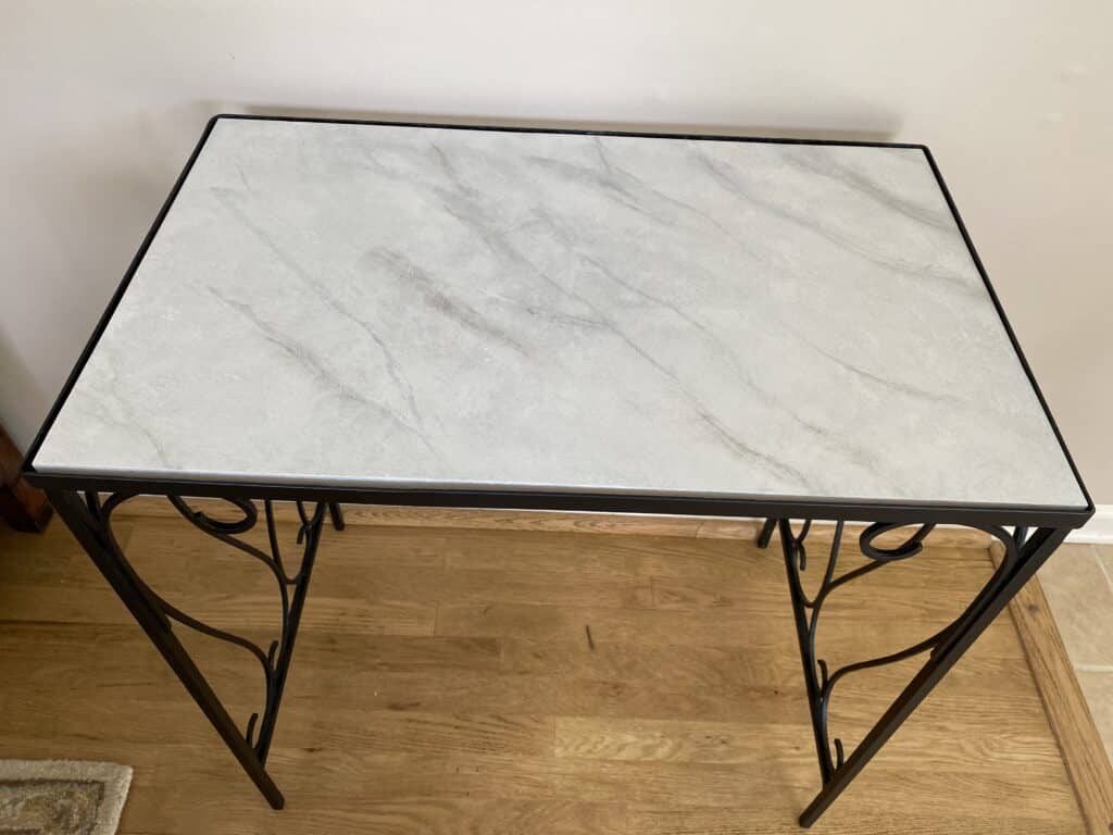 Wrought iron table with faux marble top sitting on hardwood floor