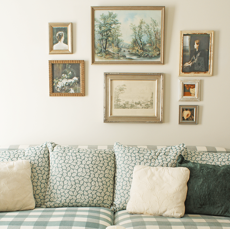 Seven framed prints on gallery wall above a green sofa