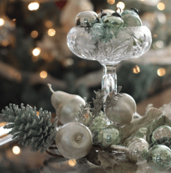 Vintage ornaments in an antique glass compote displayed on a coffee table