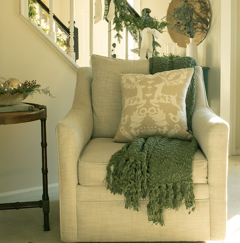 A swivel chair with a nordic style pillow and a cozy green throw