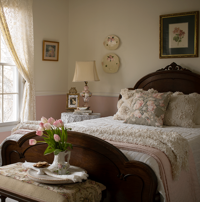 An English bedroom showing a bed in front of a window with a lace curtain