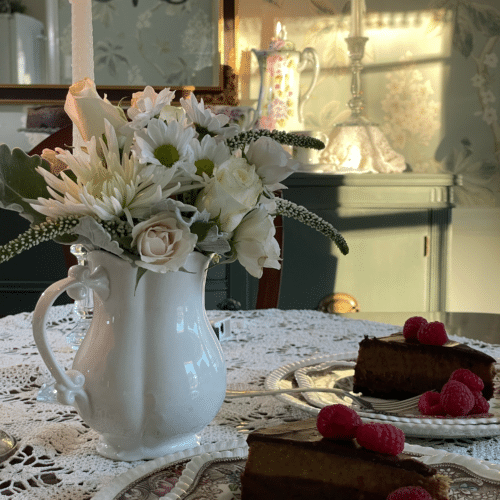 two slices of chocolate mocha cheesecake on vintage plates on a table with flowers