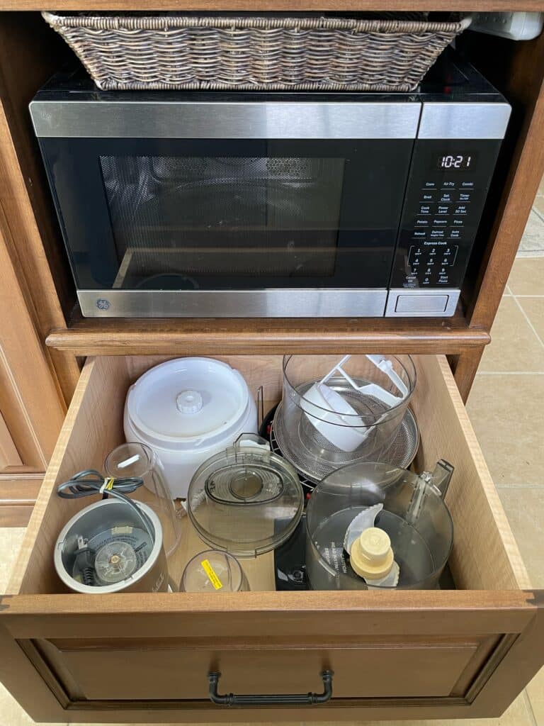 A kitchen island with a microwave opening and a large pull-out drawer