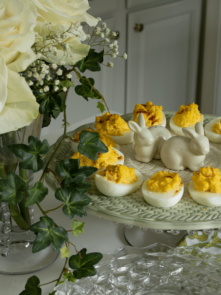 Deviled eggs on a deviled egg plate surrounded by ivy and white roses