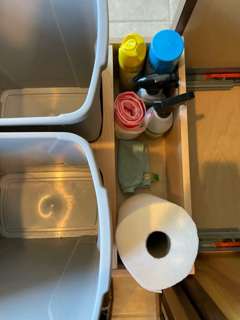 Kitchen island trash receptacle cabinet showing storage behind trash cans