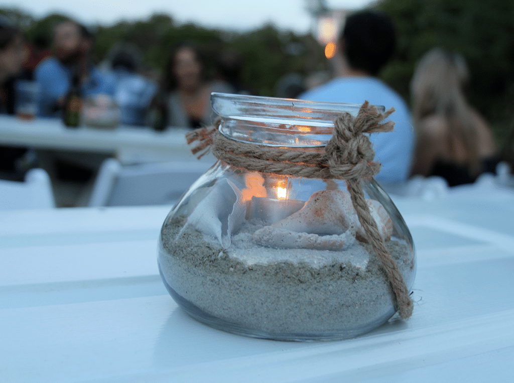 A table lantern filled with sand and shells for a beach wedding