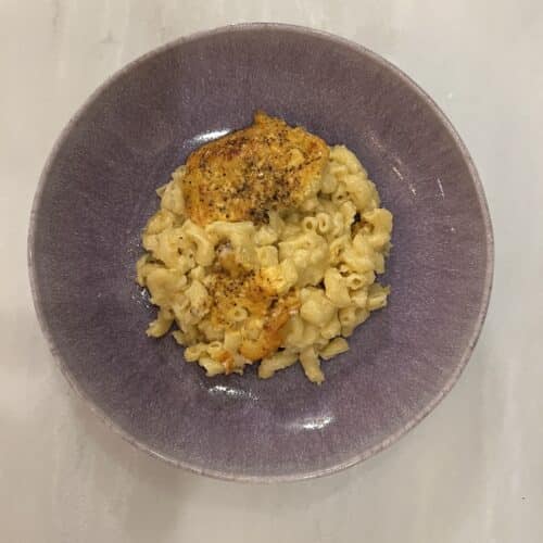 Macaroni and cheese in a purple bowl on a marble table top