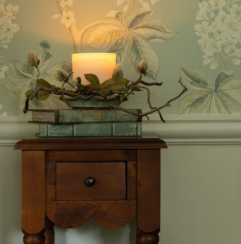 A fall scented candle styled using books and sticks.