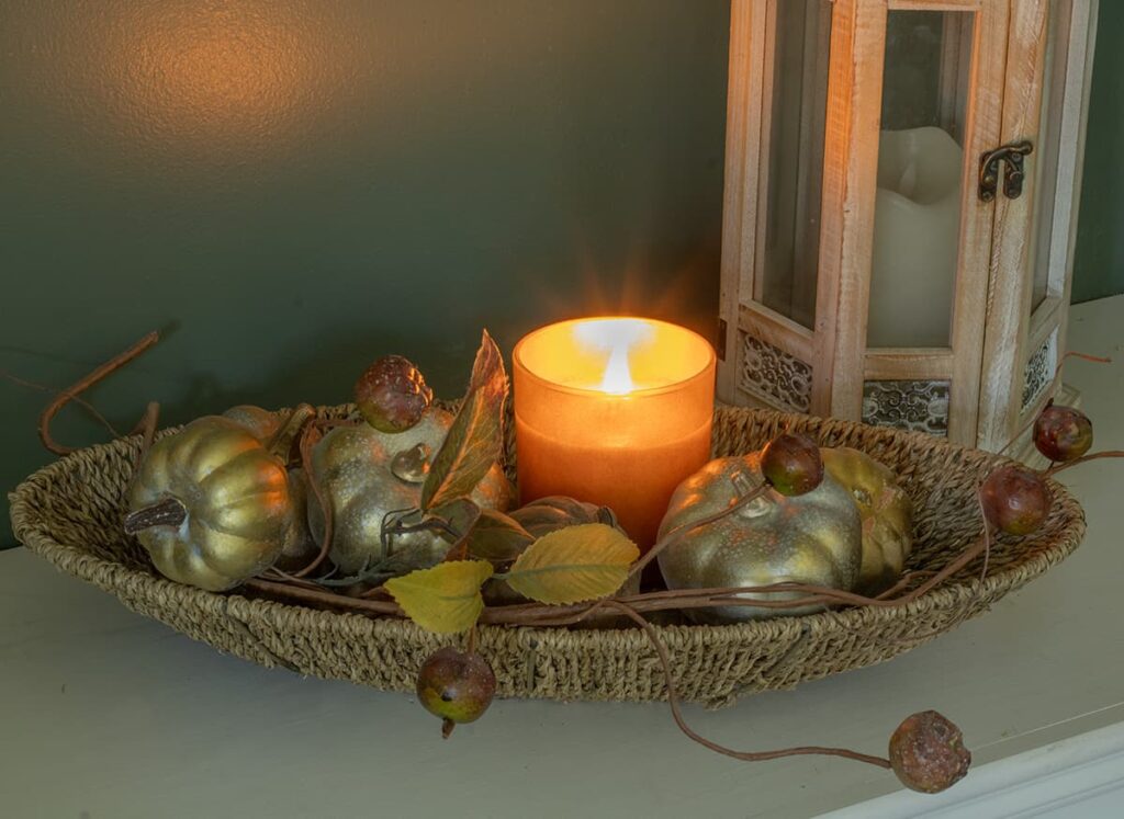 A dough bowl holding a candle and mini pumpkins.