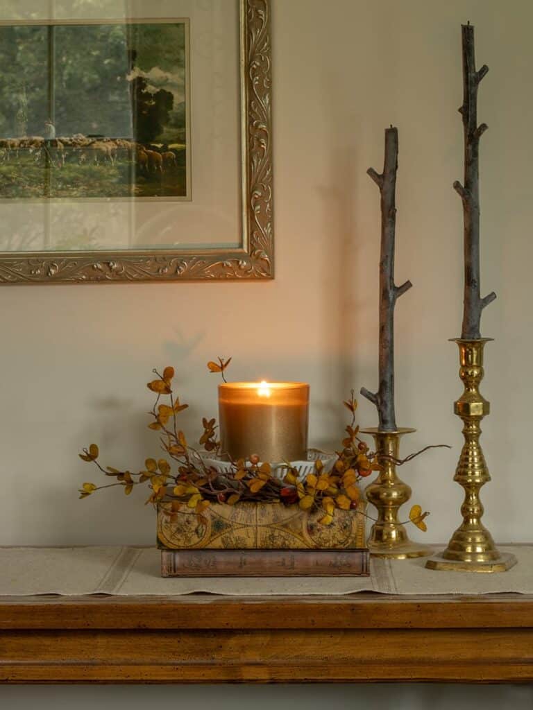 An example of a scented candle displayed in vintage dishware and surrounded by a fall wreath.