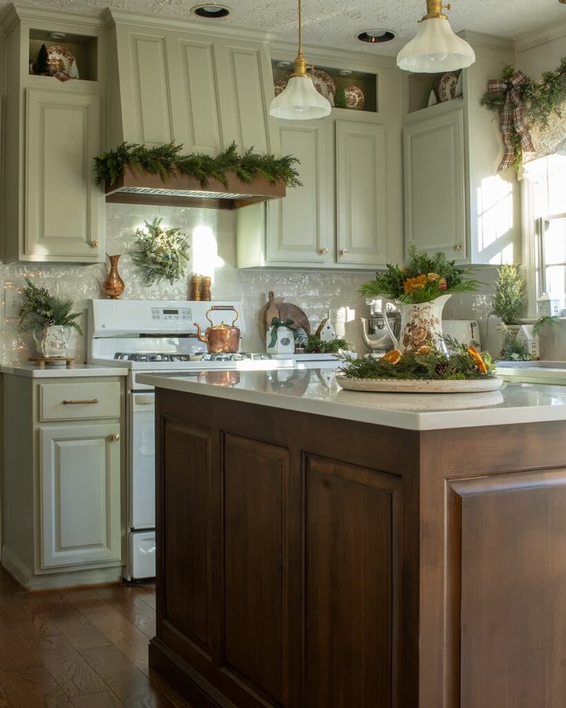 A two-tone kitchen with green painted cabinets and a wood tone island