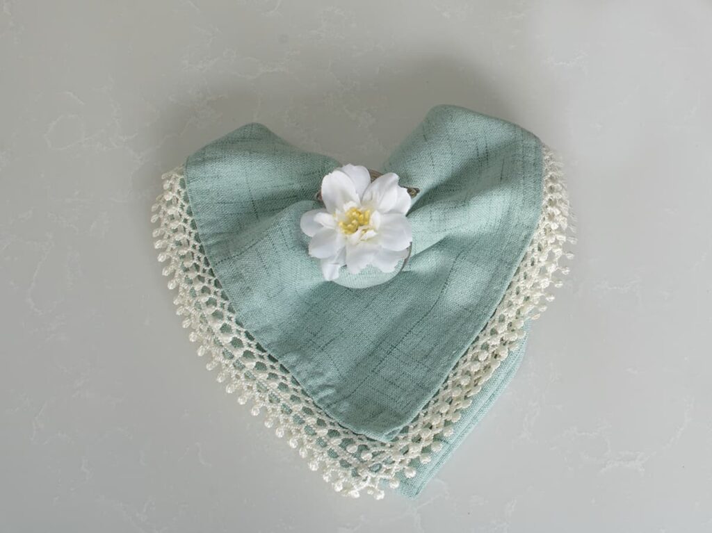 A heart-shaped napkin fold topped with a flower embellishment