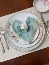 A napkin folded into a heart shape on a vintage plate stack