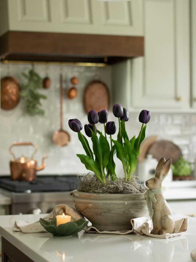 Tulips in a cachepot on a kitchen island with a copper potrail in the background